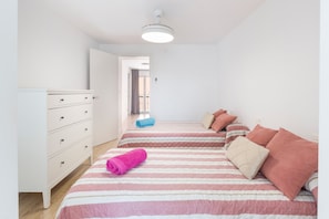 Camera da letto con due letti, una cassettiera e una lampada a soffitto.