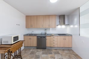 Una cucina compatta con mobili in legno, lavastoviglie, forno a microonde e lavello.