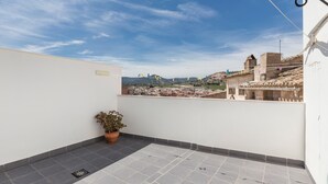 A rooftop terrace with a potted plant, a drain, and a view of a cityscape with buildings and mountains. - Holiday Home 'Parraga' with Mountain View, Private Terrace and Balcony (Cehejín)