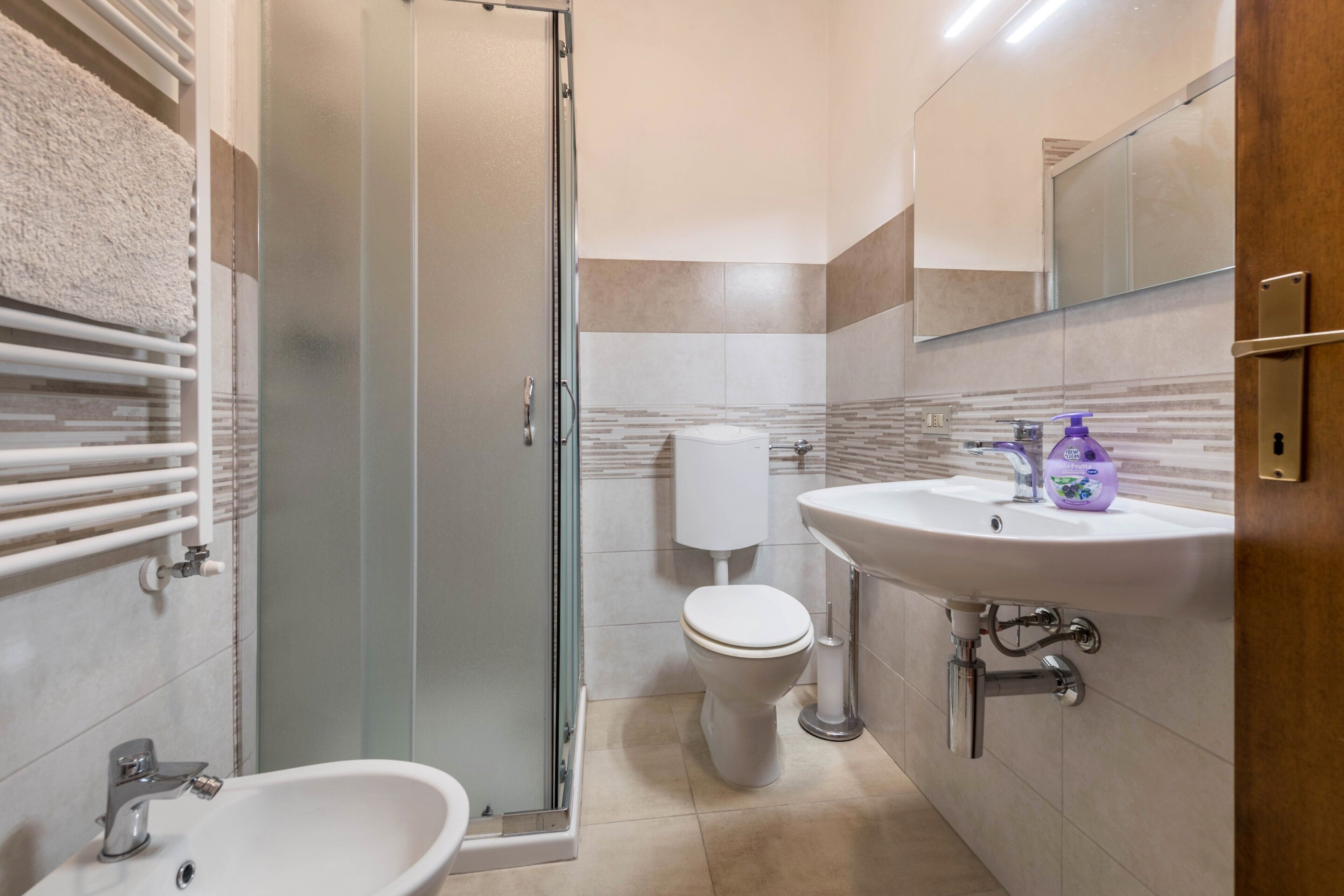 A bathroom with a glass shower enclosure, a white sink, and a toilet.