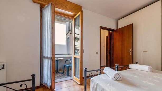 Un dormitorio con cama, una puerta de madera, una ventana y vistas a un área exterior.