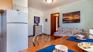 Un espacio habitable compacto con kitchenette, comedor y sofá.
