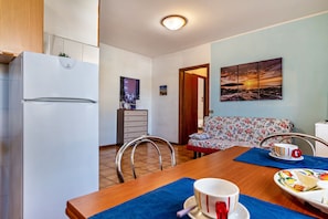 A compact living space with a kitchenette, a dining area, and a sofa.