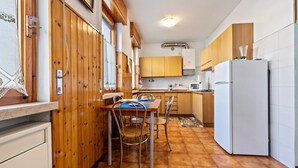 Una cocina con armarios de madera, un refrigerador blanco y una mesa de comedor con sillas.