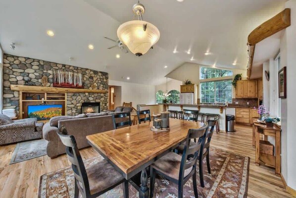A spacious living area with a fireplace, a dining table, and a kitchen area with wooden cabinets.