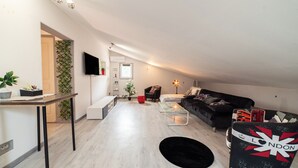A modern living room with a sofa, a coffee table, a TV, and a plant.