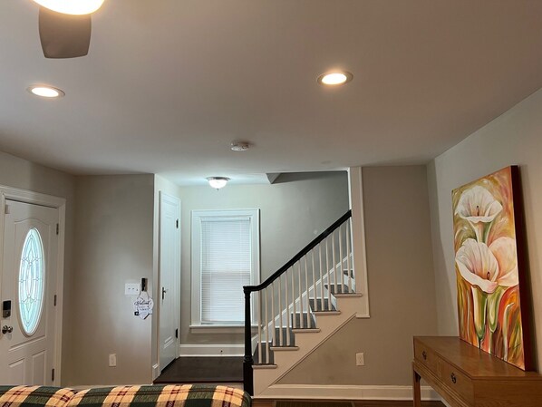 Una habitación con una escalera, una puerta con un vitral y un cuadro en la pared.