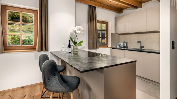 Una cocina moderna con una isla central, vigas de madera y ventanas amplias.