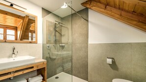 Un baño moderno con ducha de vidrio, tocador de madera con lavamanos y un inodoro.