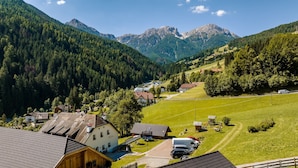 Un pueblo rural con casas, un parque infantil y montañas al fondo.