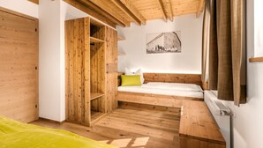 A small, wooden room with a loft bed, a wooden wardrobe, and a radiator. - Apartment "Perfila Dolomitenblick" with Mountain View, Shared Garden & Wi-Fi (Valdaora)