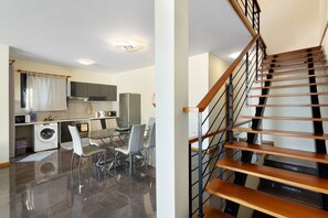 A modern kitchen with a dining area, a washing machine, and a staircase.