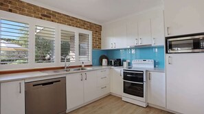 A kitchen with white cabinets, a dishwasher, a stove, and a microwave.