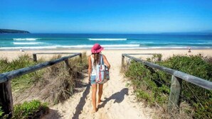 Un sentiero sulla spiaggia che conduce verso l'oceano, con una persona che cammina.