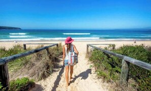 A beach path leading to the ocean with a person walking.