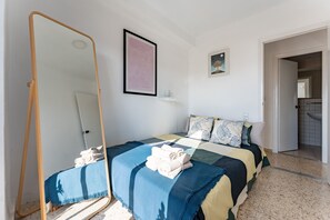 Un dormitorio con cama, espejo, un cuadro enmarco y una puerta que da a un baño.