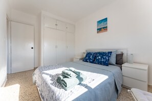 A bedroom with a bed, a nightstand, a wardrobe, and a painting on the wall.