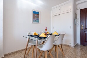 Un comedor con una mesa de vidrio, sillas blancas y un cuadro en la pared.