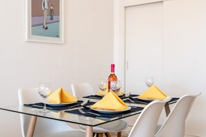 A dining table set with yellow napkins, wine glasses, and a bottle of wine.