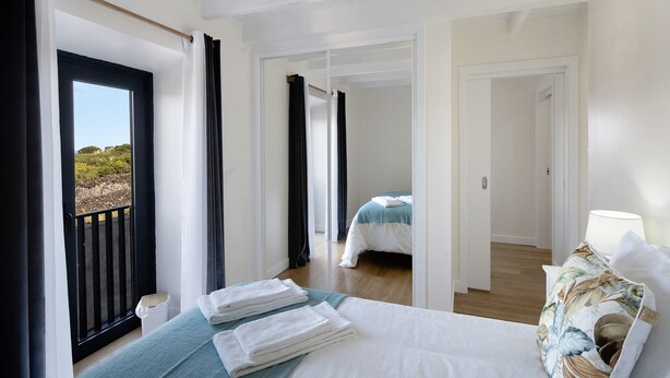 Une chambre d’hôtel avec un lit, une vue sur l’extérieur par une porte et un balcon.