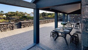 Un espace extérieur aménagé en terrasse, avec des tables et des chaises, des murs en pierre et une vue sur le paysage environnant.