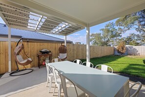 Relax in a serene outdoor setting with a covered patio featuring a long table and comfortable seating.