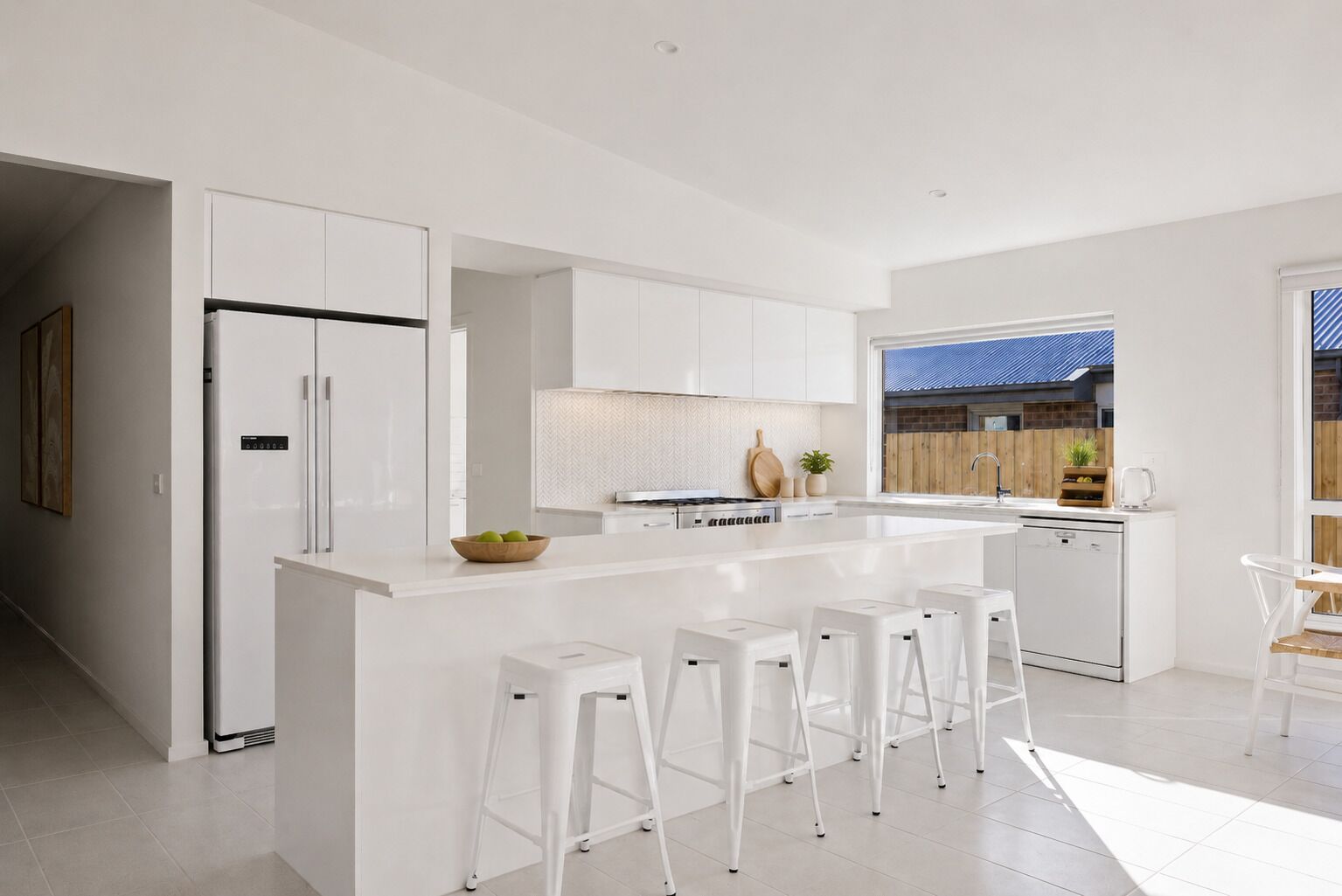 A modern kitchen with a central island, white cabinetry, and bar stools.