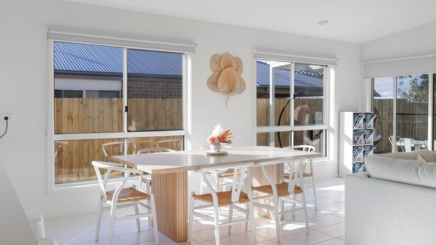 A bright, spacious kitchen with a large island, white cabinetry, and a view of the backyard through large windows.