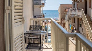 Ein Balkon mit Tisch und Stühlen mit Blick auf einen Strand und angrenzende Gebäude.