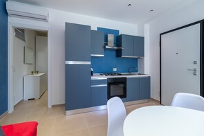 Une cuisine moderne avec des meubles bleus, une cuisinière et un évier. On y trouve également une table à manger avec des chaises.
