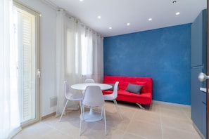 Una habitación con una mesa de comedor y sillas, un sofá rojo y una pared azul de acento.