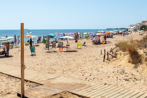 Una playa con pasarelas de madera, sillas de playa, sombrillas y una vista despejada del mar.