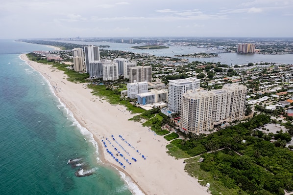 An aerial view of a coastal city with a beachfront, high-rise buildings, and a marina.
