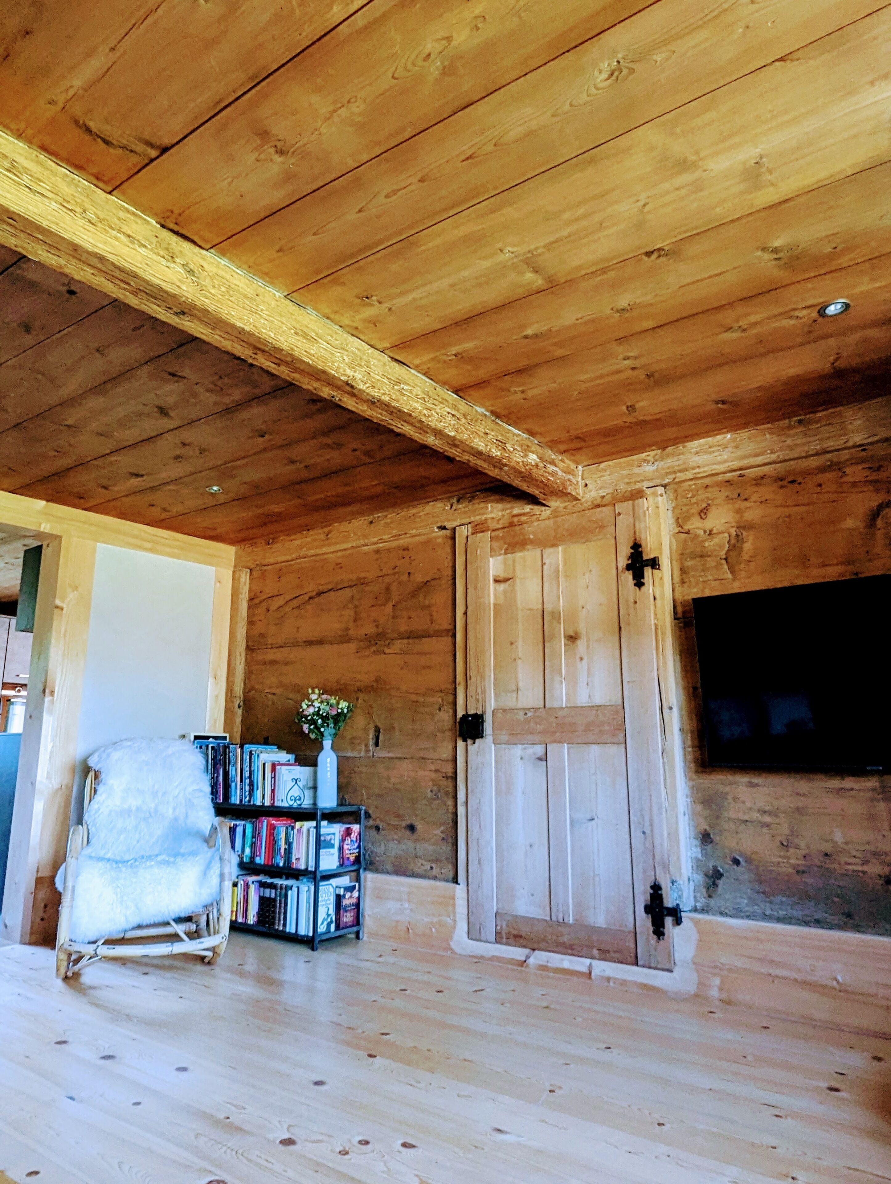 A wooden interior with a bookshelf, a white chair, and a door.