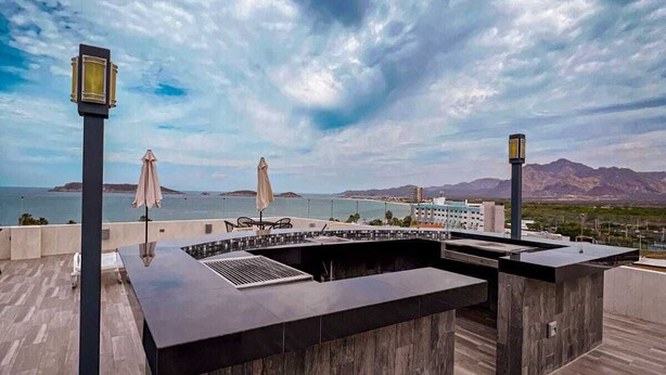 Une terrasse sur le toit équipée d’une table de billard, de coins salon extérieurs et offrant une vue sur la mer et les montagnes.