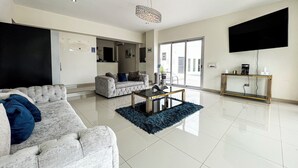 Un salon moderne avec un grand canapé, une table basse et un téléviseur fixé au mur.