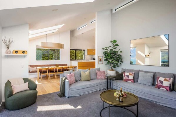 A modern living room with a sofa, coffee table, and a dining area with chairs and a table.