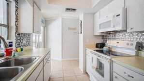 A compact kitchen with white cabinets, a built-in oven, a microwave, and a kettle on the stove. - Family Oasis--Private Pool & Hot Tub-Near Anna Maria Island, Beaches, Parks, Shops (Bradenton)
