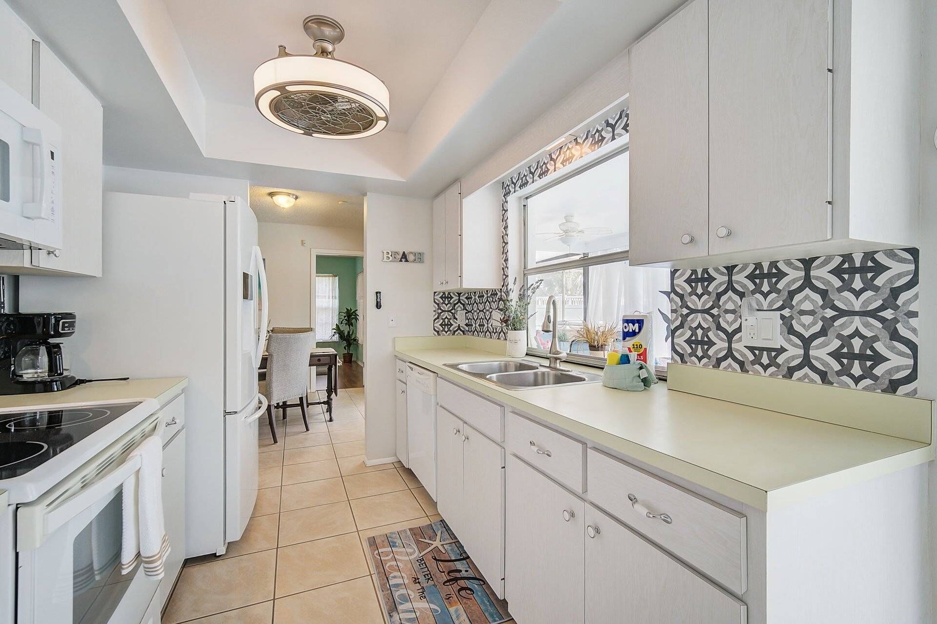 A modern kitchen with white cabinets, a black coffee machine, and a patterned backsplash.