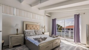 Una camera da letto con un letto grande, due comodini, una finestra con tende e vista sugli edifici.
