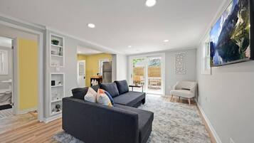 Un salon moderne avec un canapé gris, un fauteuil blanc et un grand tableau accroché au mur.