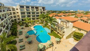 A hotel with a pool area, multiple balconies, and a view of the surrounding neighborhood. - 2BR Duplex Palmaruba Condos w Great Location (Noord)