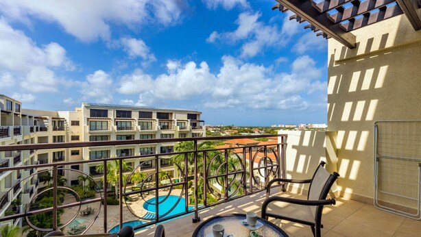 A balcony with a view of a swimming pool and a multi-story building. - 2BR Duplex Palmaruba Condos w Great Location (Noord)