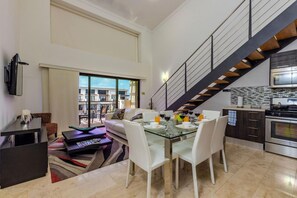 Enjoy a spacious living area with a high ceiling, large window, and comfortable seating for relaxation.