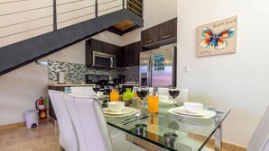A modern kitchen with dark wood cabinets, stainless steel appliances, and a glass dining table set for four. - 2BR Duplex Palmaruba Condos w Great Location (Noord)
