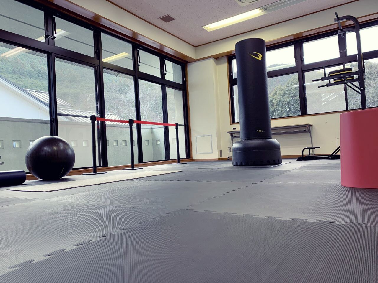 A gym with exercise equipment, large windows, and a view of the outdoors.