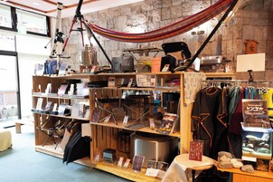Una tienda con estantes llenos de libros, equipo de camping y una hamaca.