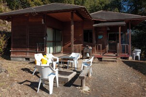 Una cabaña de madera con porche, mobiliario exterior y una pequeña mesa.