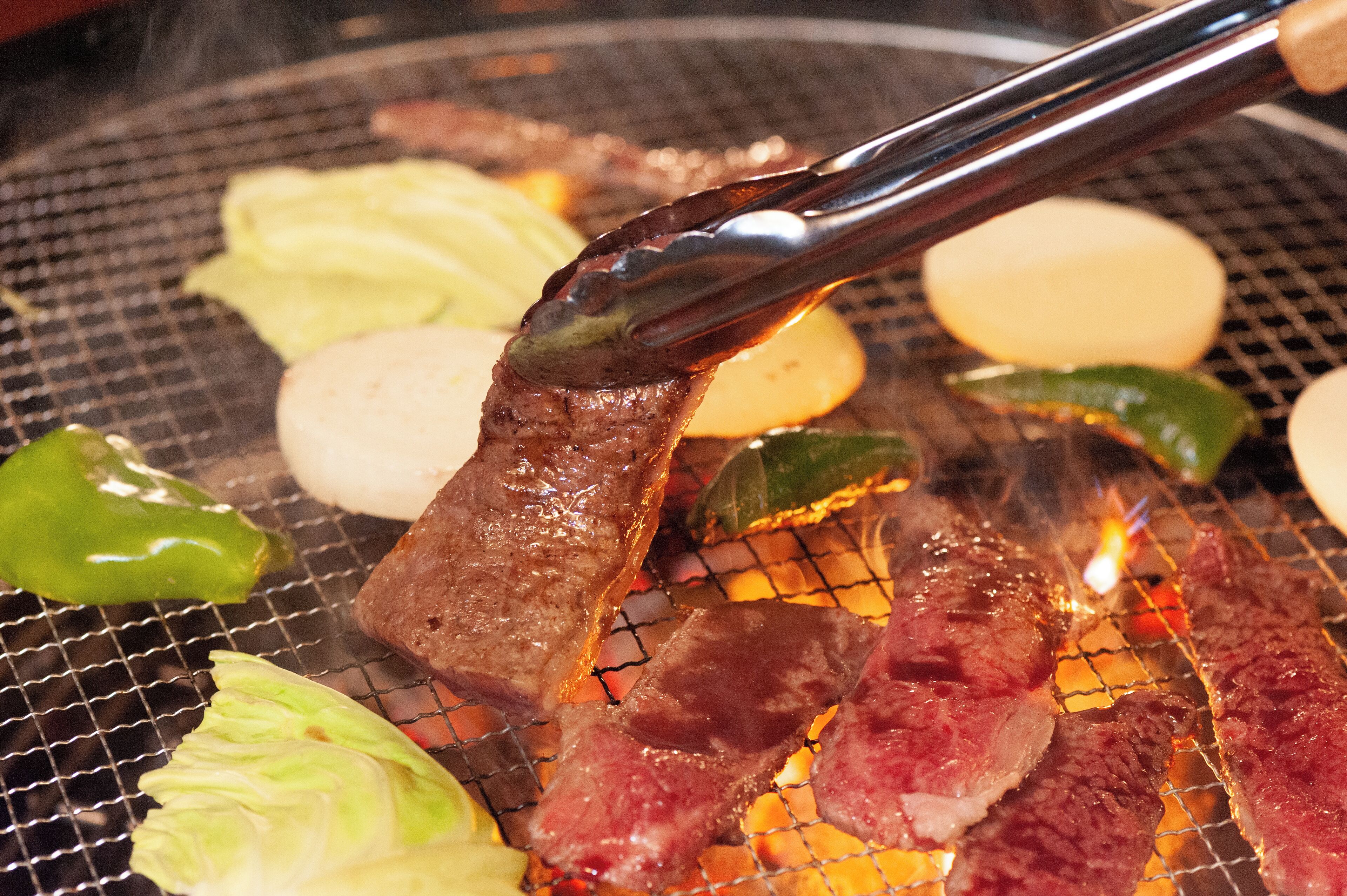 A grill with various meats and vegetables being cooked.