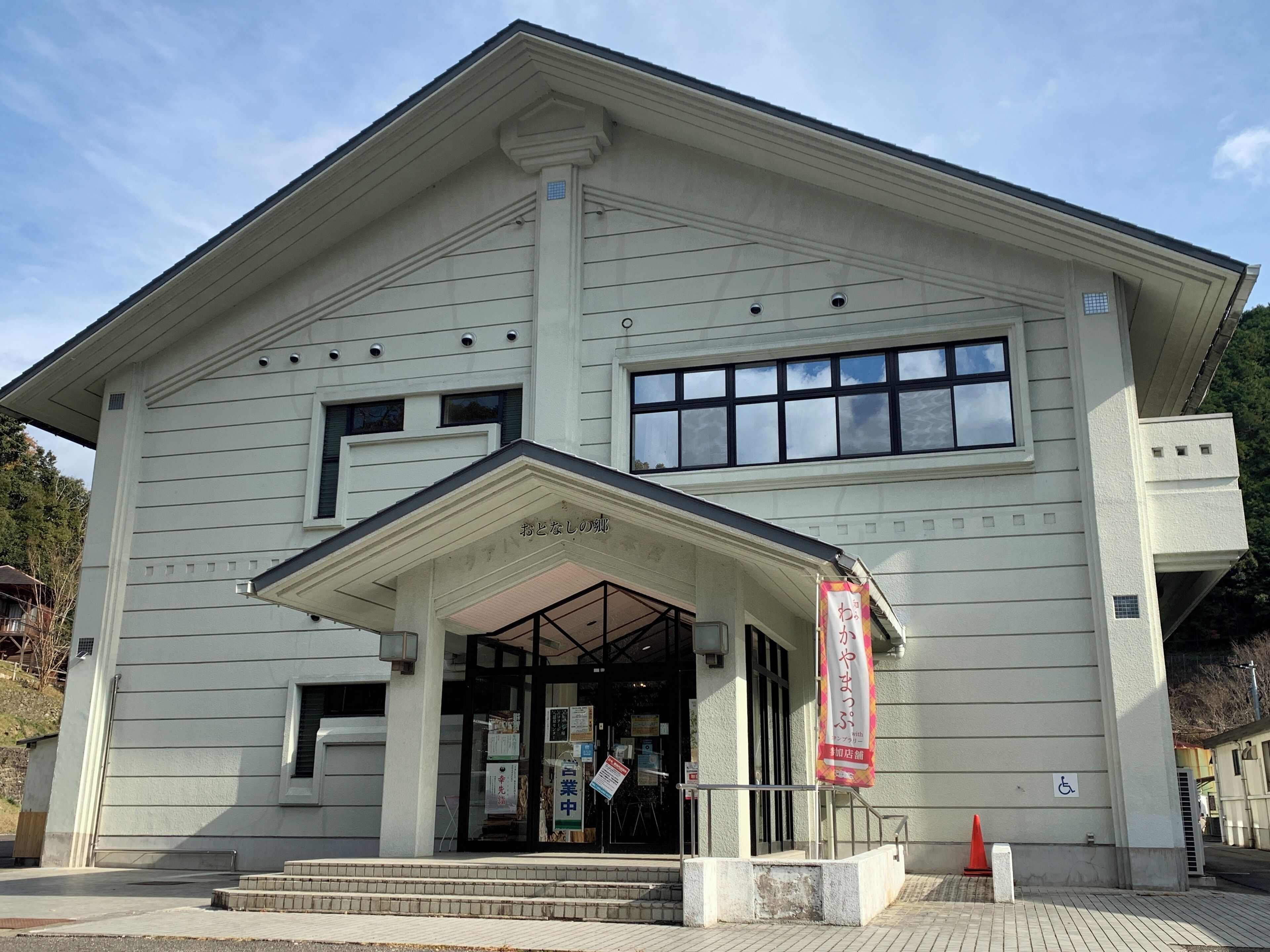 A building with a large entrance, a banner, and a wheelchair accessibility sign.